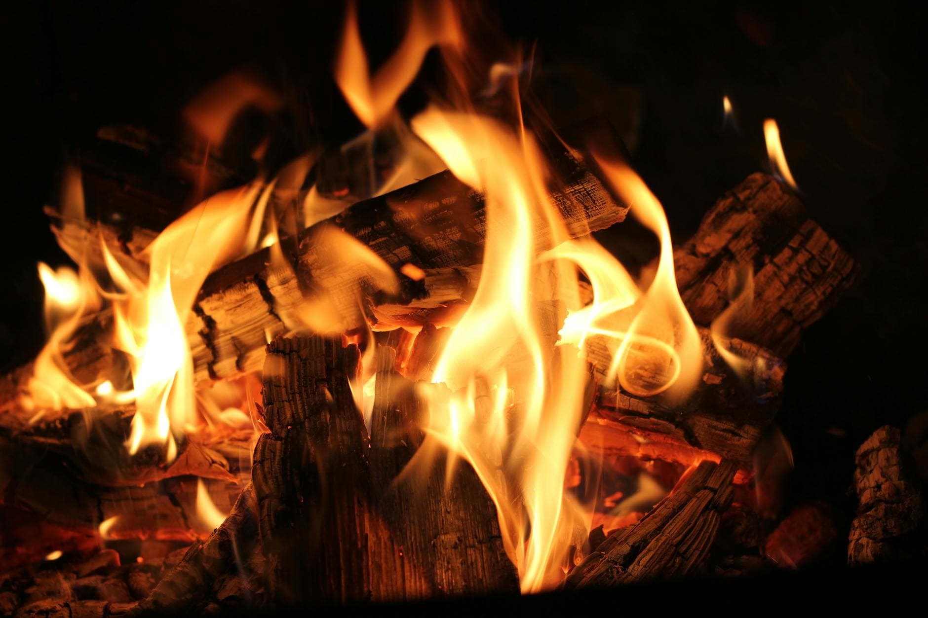 Warm and inviting close-up view of a burning fireplace with glowing wood logs and flames.